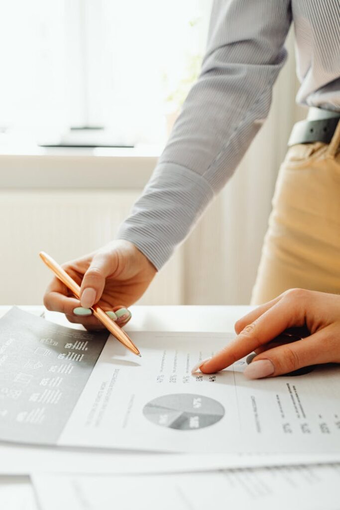 Close-up of hands reviewing financial documents and graphs in an office setting.